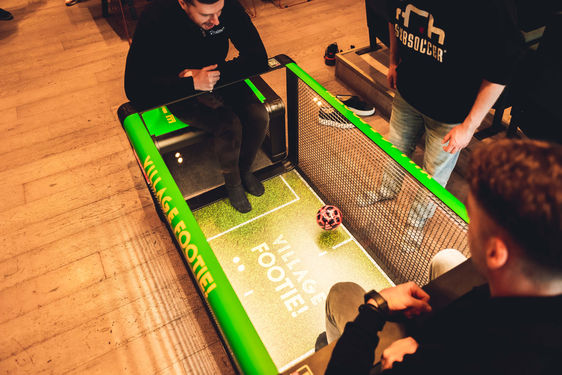 A fully wrapped Subsoccer table branded 'Village Footie!' mid-game